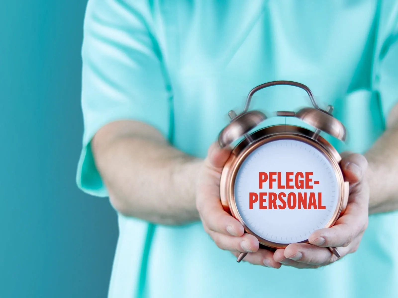 Eine Uhr mit der Anschrift Pflege-Personal in den Händen eines Pflegers.
